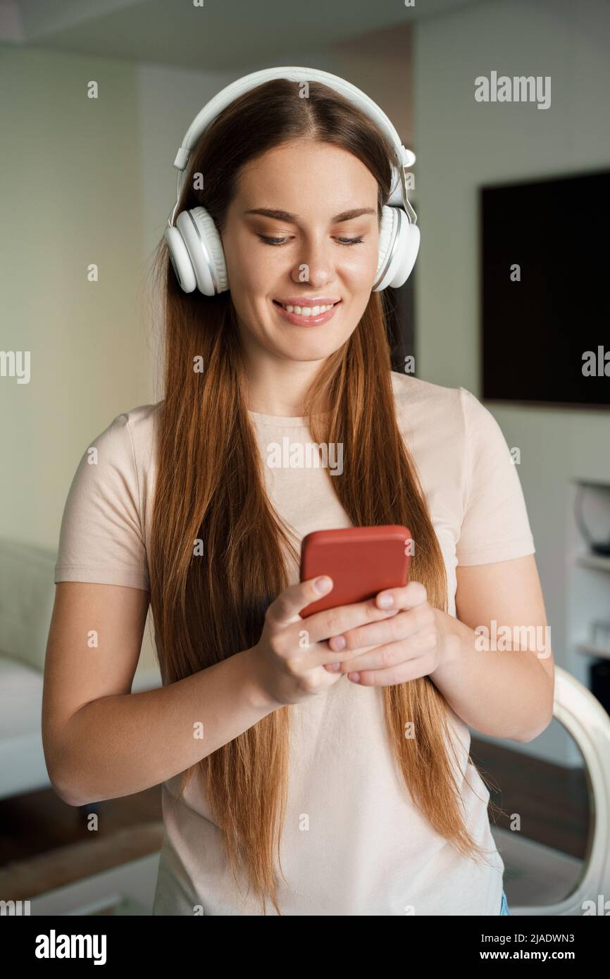 Smiling young woman teenager n headphone holding smartphone portrait Stock Photo