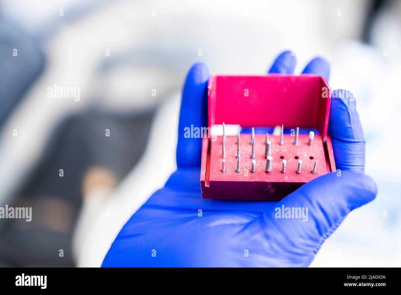 Dentist's hand with blue rubber glove on, holding a composite polishing kit. Stomatology concept. Selective focus. Stock Photo