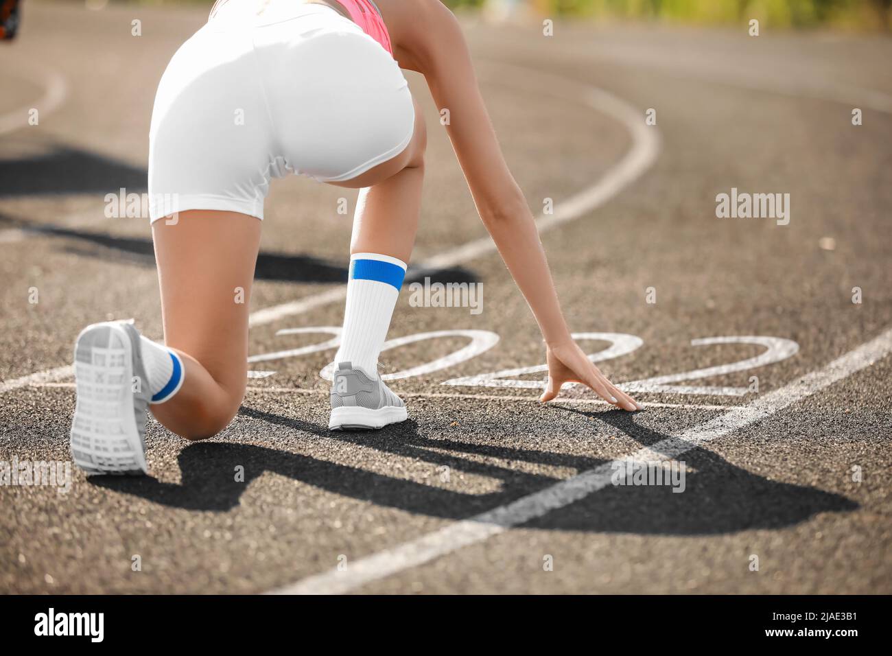 Sporty young woman in crouch start position near figure 2022 on running ...