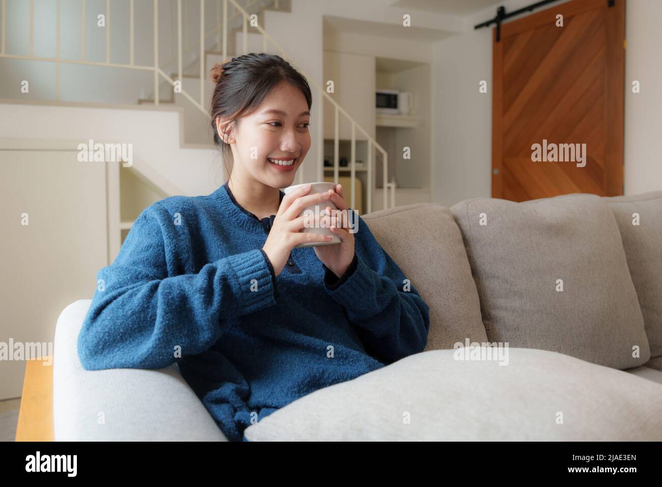 Excited young Asian woman watching television programs with remote controller. Lifestyle and spends leisure at home. Stock Photo