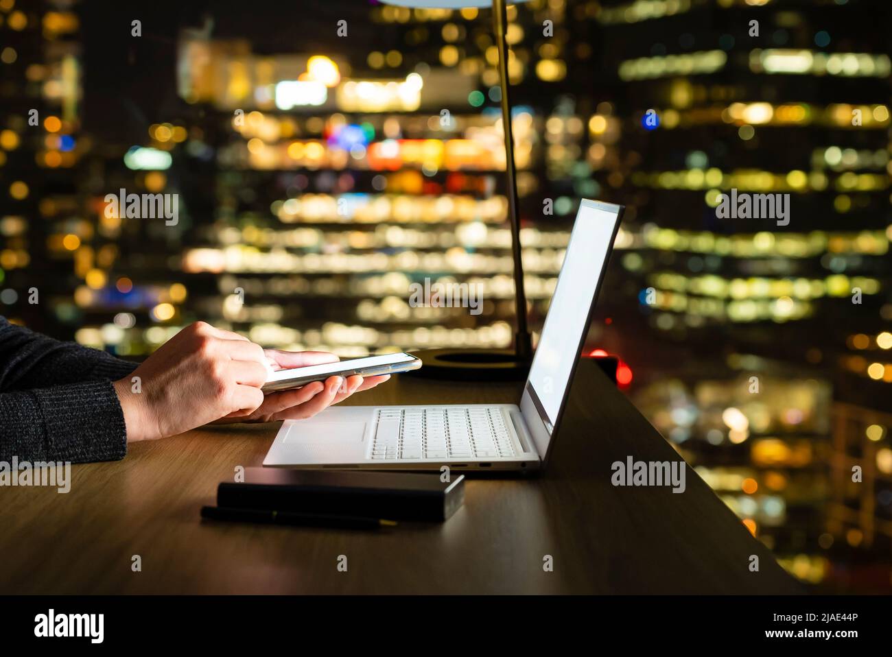 Using smartphone at night, with out focus city skyline background Stock Photo