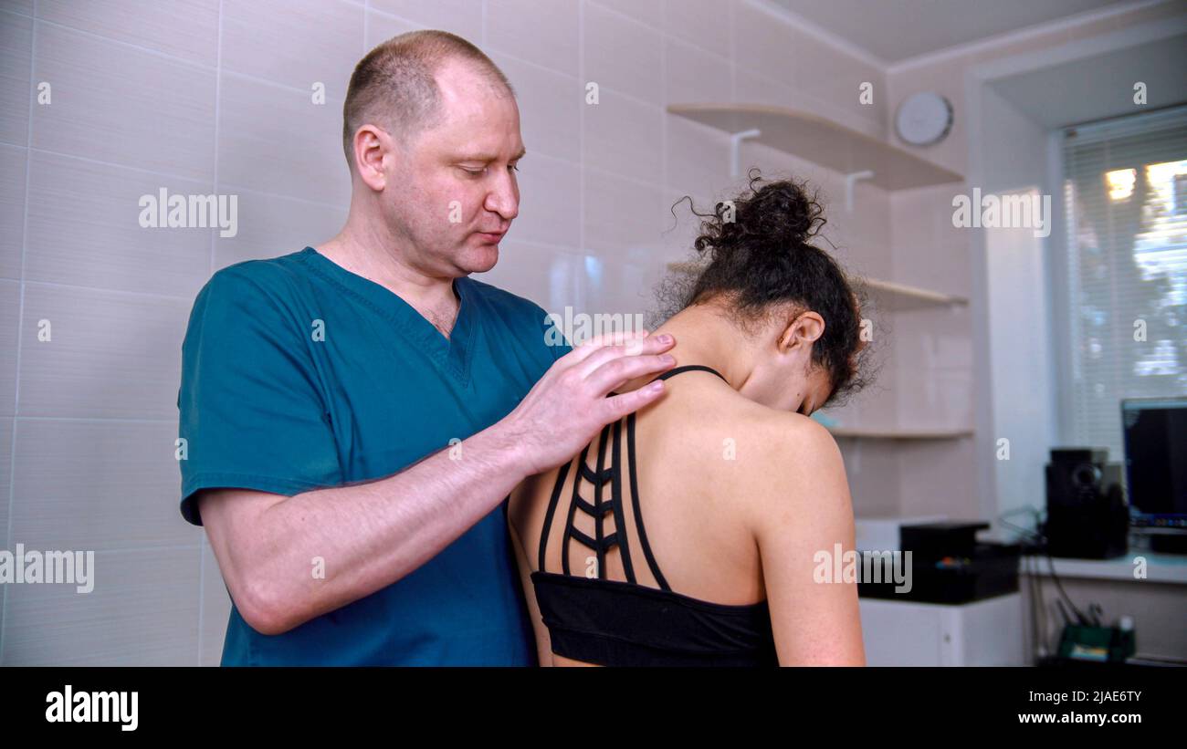 Chiropractic treatment - the doctor inspecting the young woman before the session - bending the neck down Stock Photo