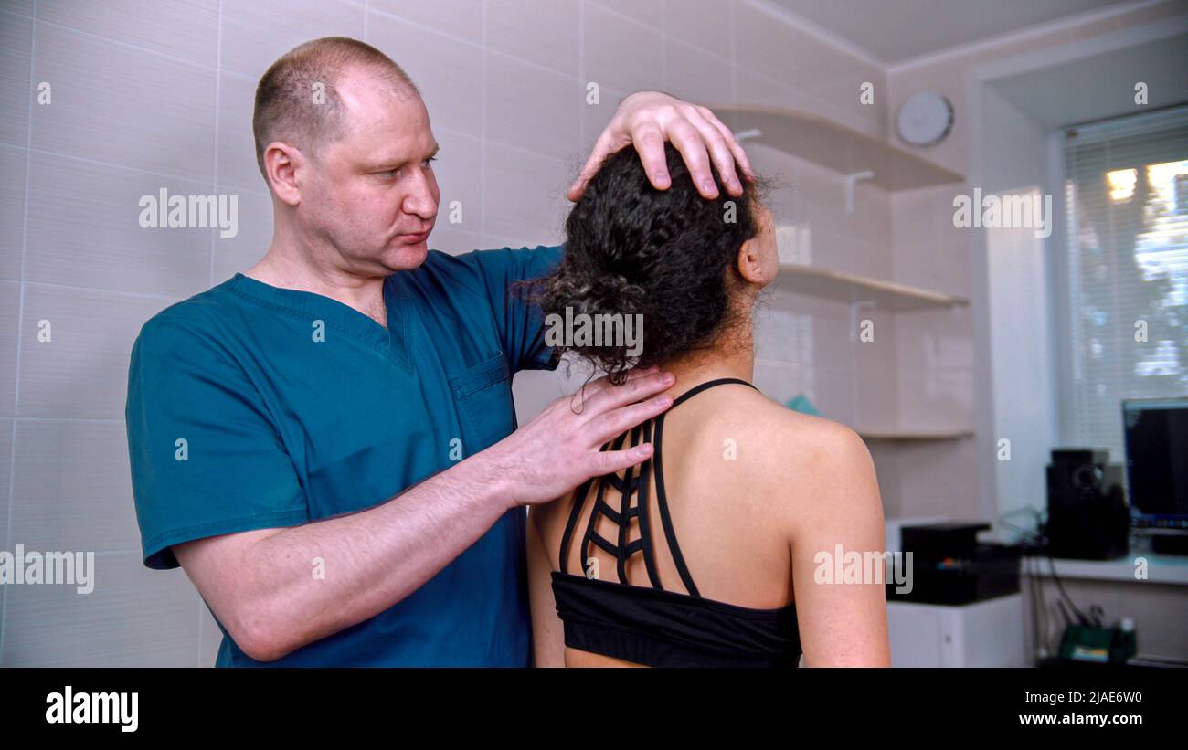 Chiropractic treatment - the doctor inspecting the young woman before the session - bending the neck up Stock Photo