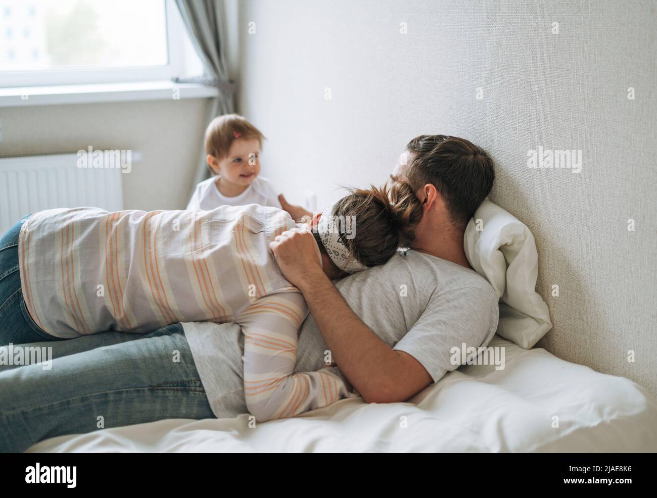 Young happy family with baby girl on bed at home Stock Photo