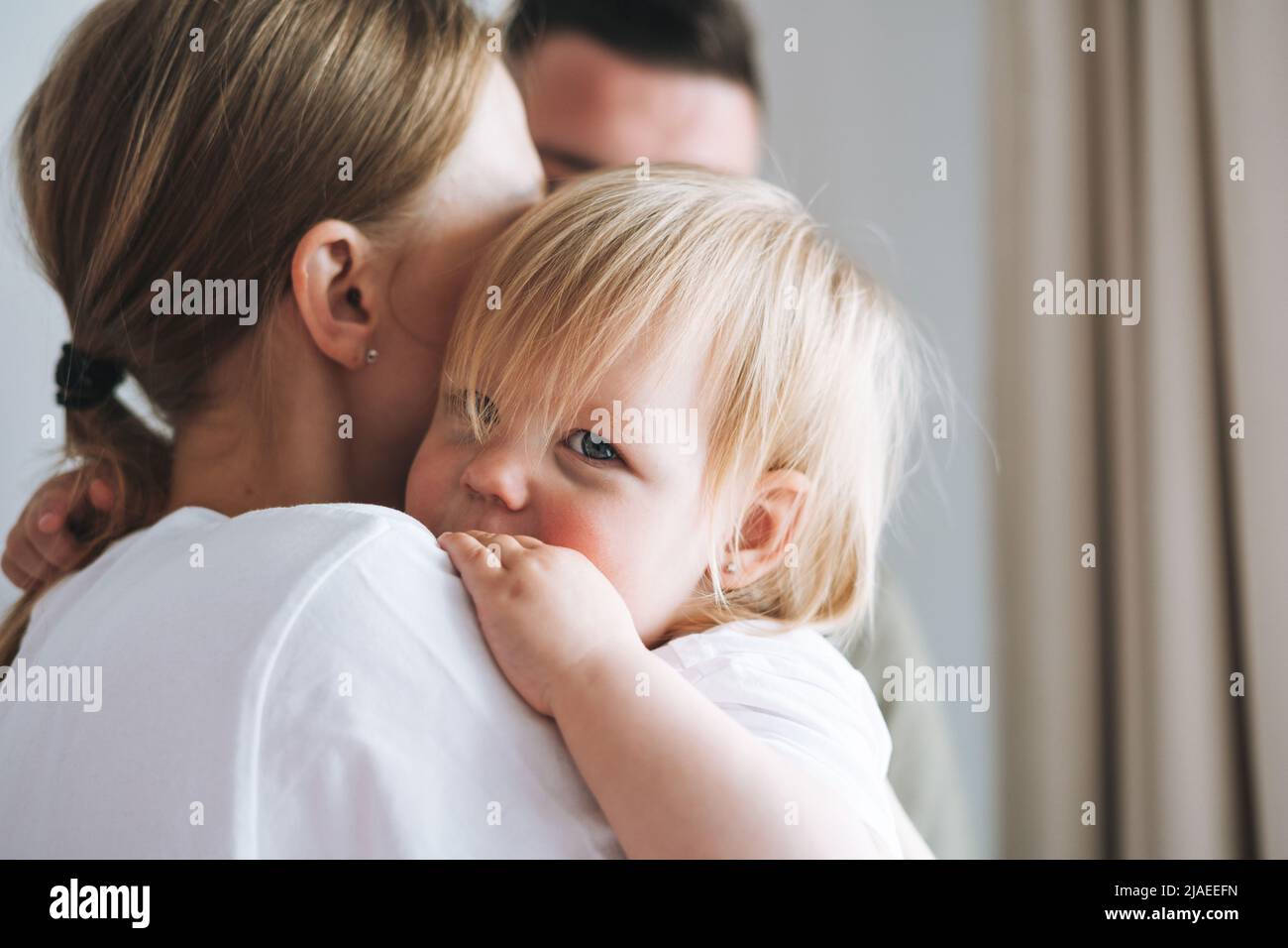 Close up portrait of family father young man and mother with baby girl little daughter near window at home Stock Photo