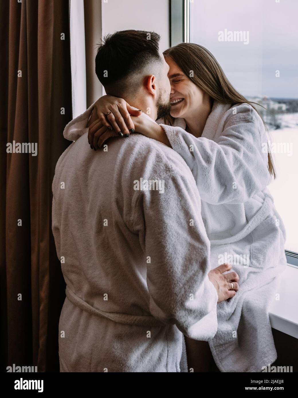 Happy couple in the hotel on window kiss and hug each other Stock Photo