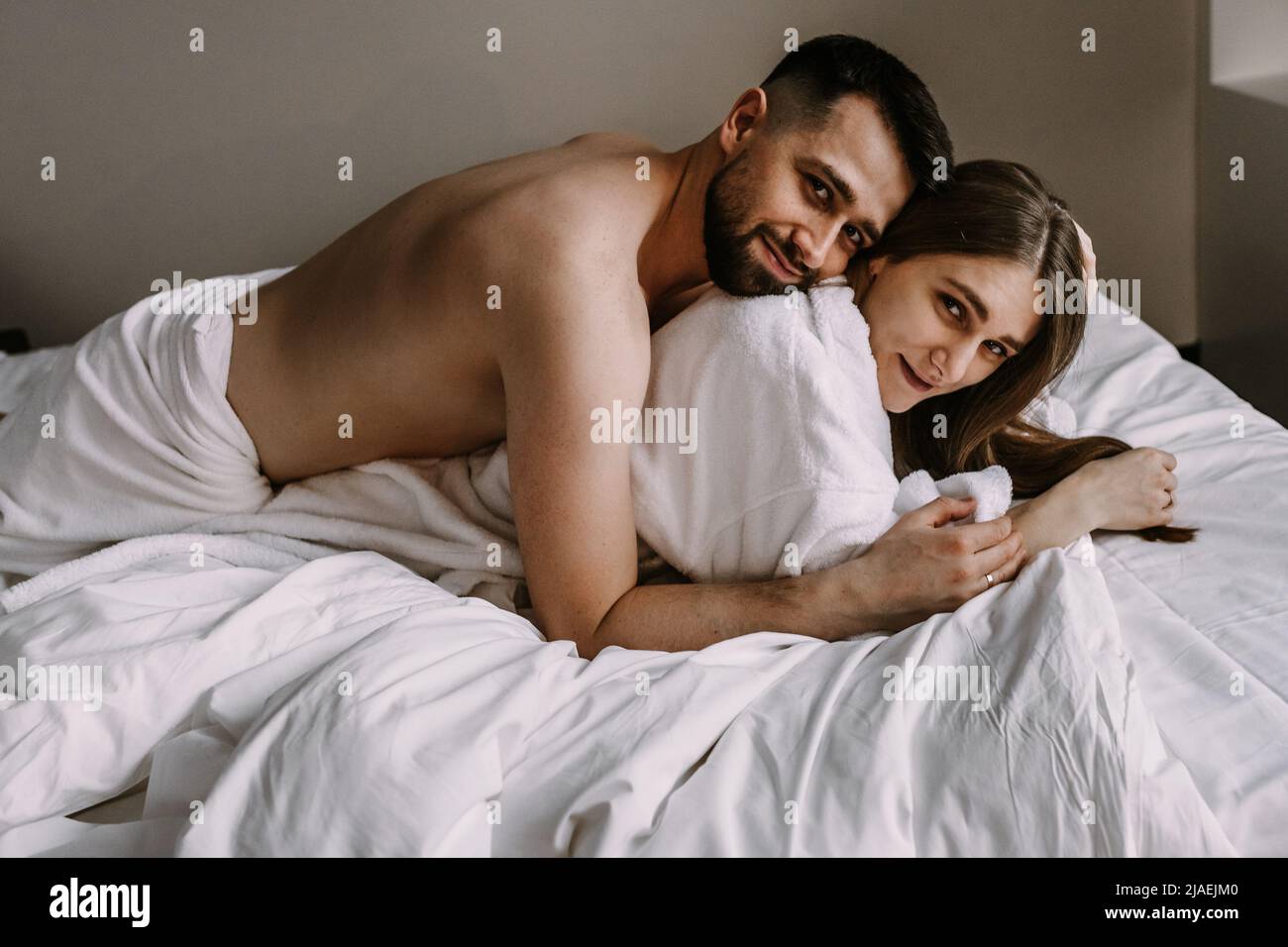 European couple hugging together while lying in bed at hotel Stock Photo