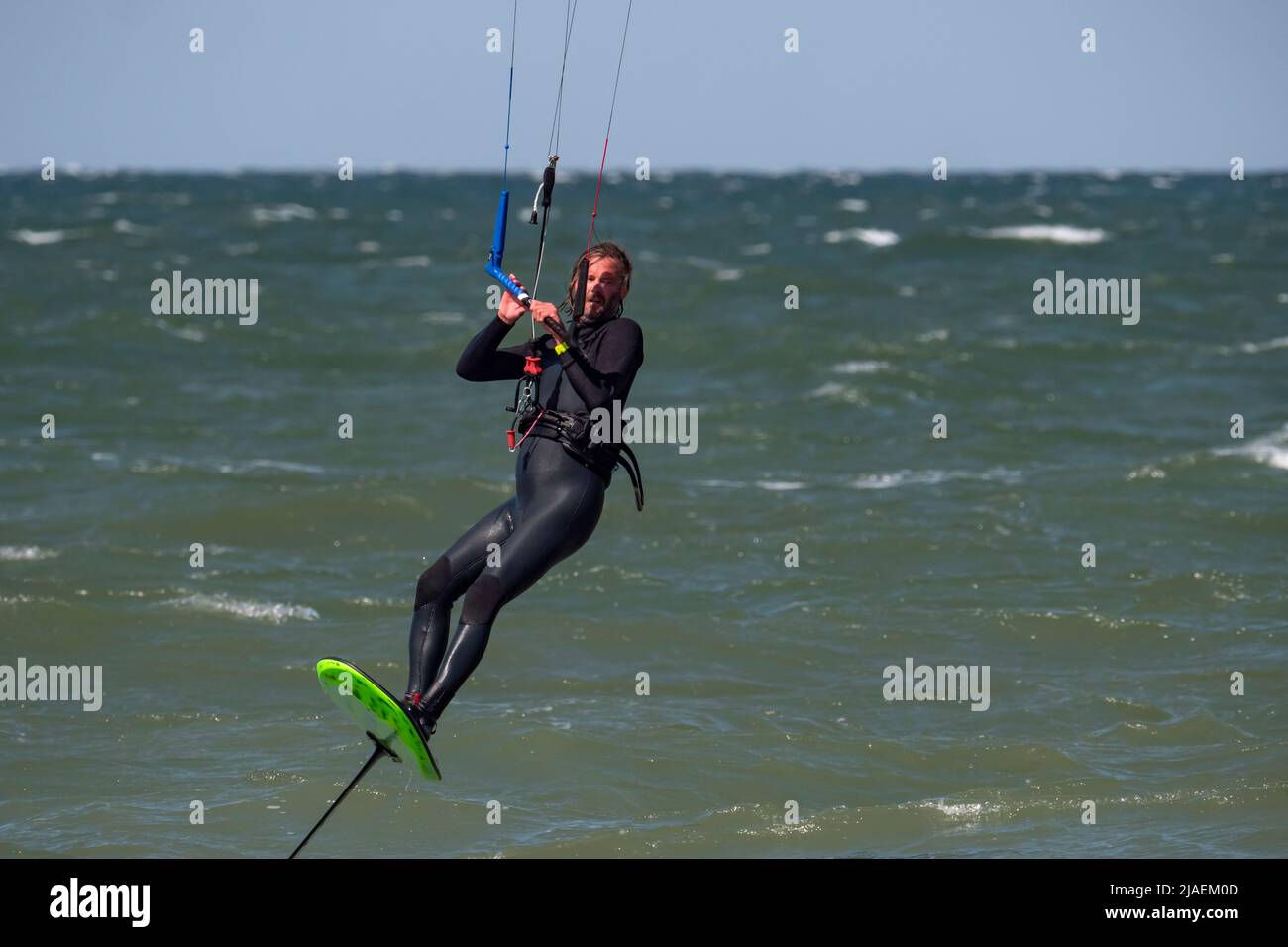 Male Kite Foil Surfer with beard and long hair on the sea Stock Photo