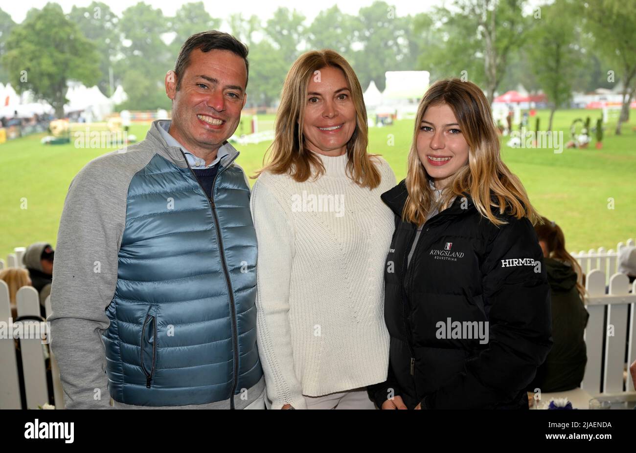 29 May 2022, Bavaria, München-Riem: Entrepreneur Christian Hirmer (l-r), his wife Christiane and their daughter, the rider Leticia, stand on the VIP tribune during the classification test of the Grand Prix of Bavaria at the Pferd International München. The Pferd International München is an event that also features a dressage and show jumping competition and a trade show area. Photo: Felix Hörhager/dpa Stock Photo
