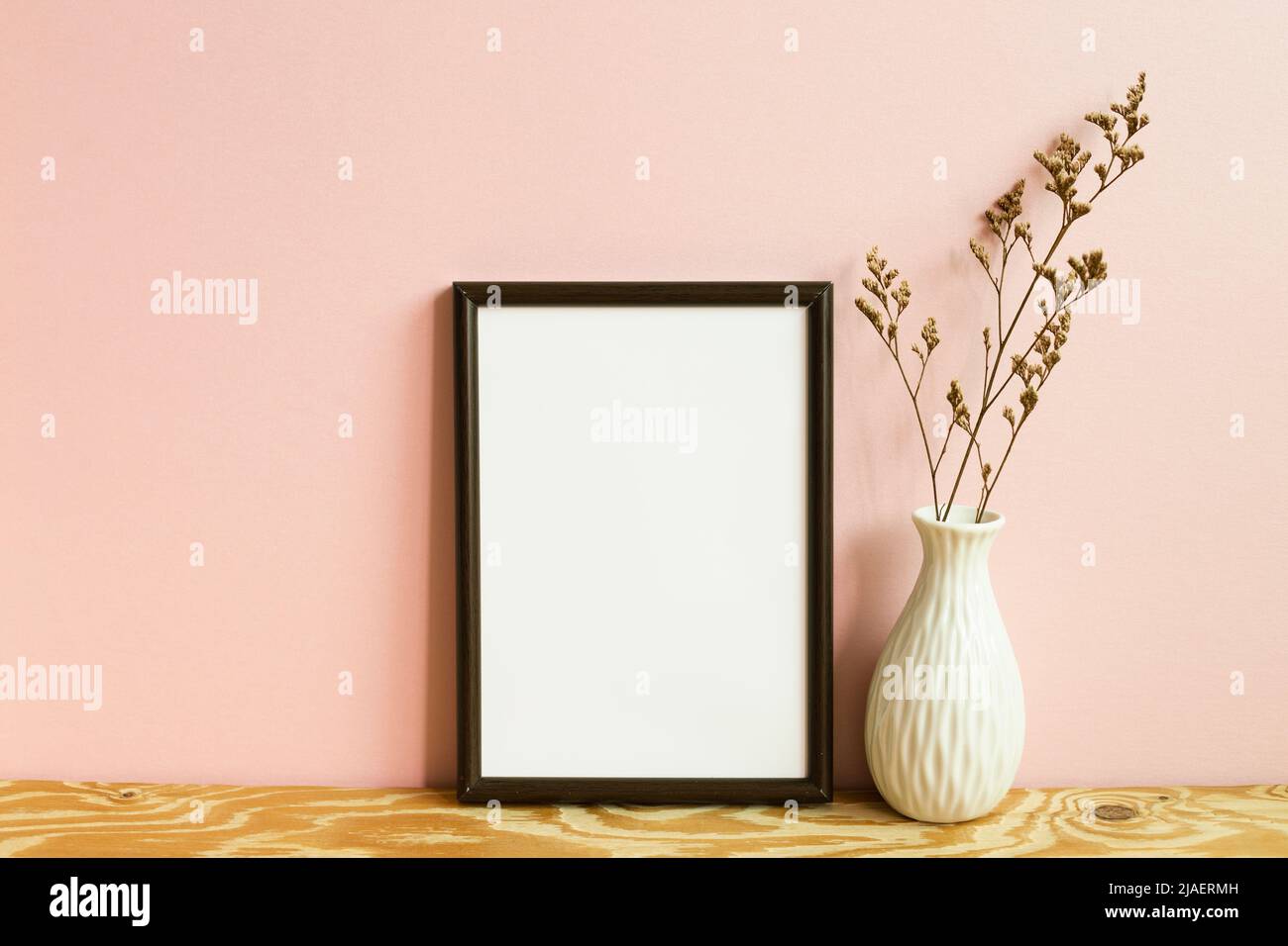 Picture frame and dry flowers on wooden table. pink wall background. copy space Stock Photo