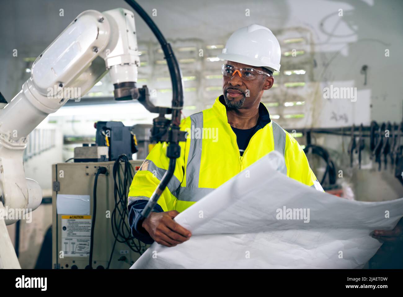African American factory worker working with adept robotic arm in a workshop . Industry robot programming software for automated manufacturing Stock Photo
