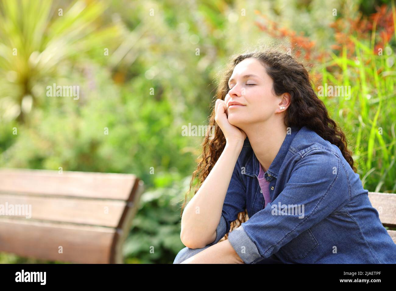 Happy woman resting with closed eyes sitting in a park Stock Photo