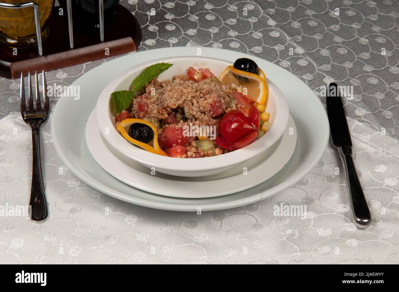 A plate of salad made of lettuce, tomato, corn, carrot, lemon and dill. Salad plate on the dining table. Stock Photo