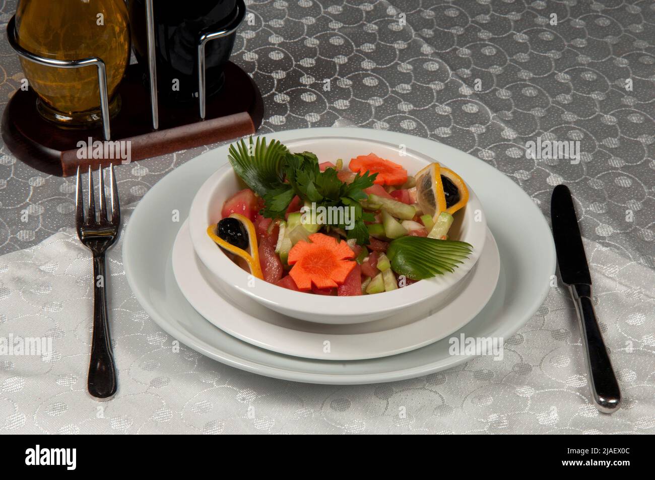 A plate of salad made of lettuce, tomato, corn, carrot, lemon and dill. Salad plate on the dining table. Stock Photo