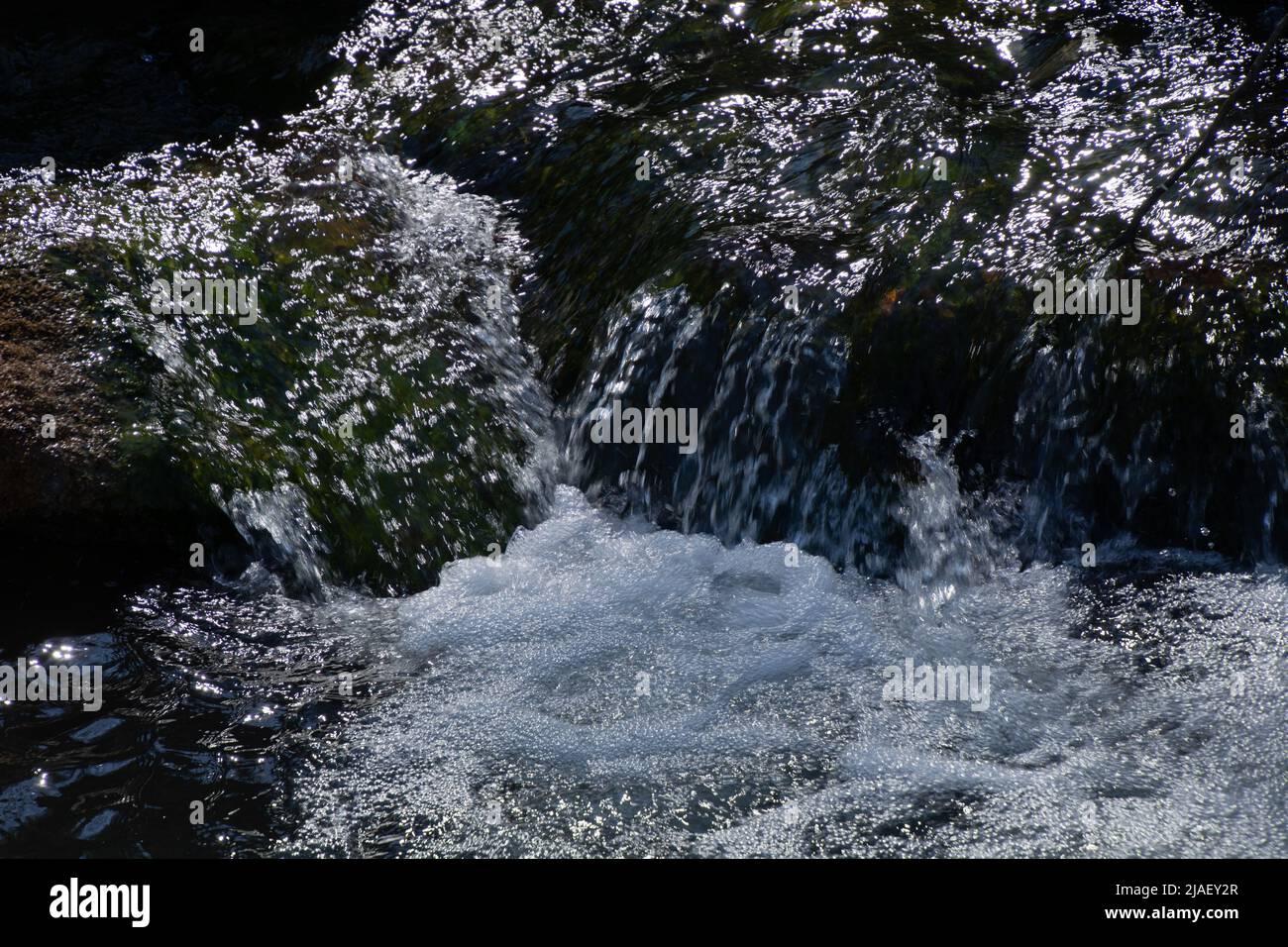 foaming whitewater with jumping water drops at a small waterfall close-up Stock Photo