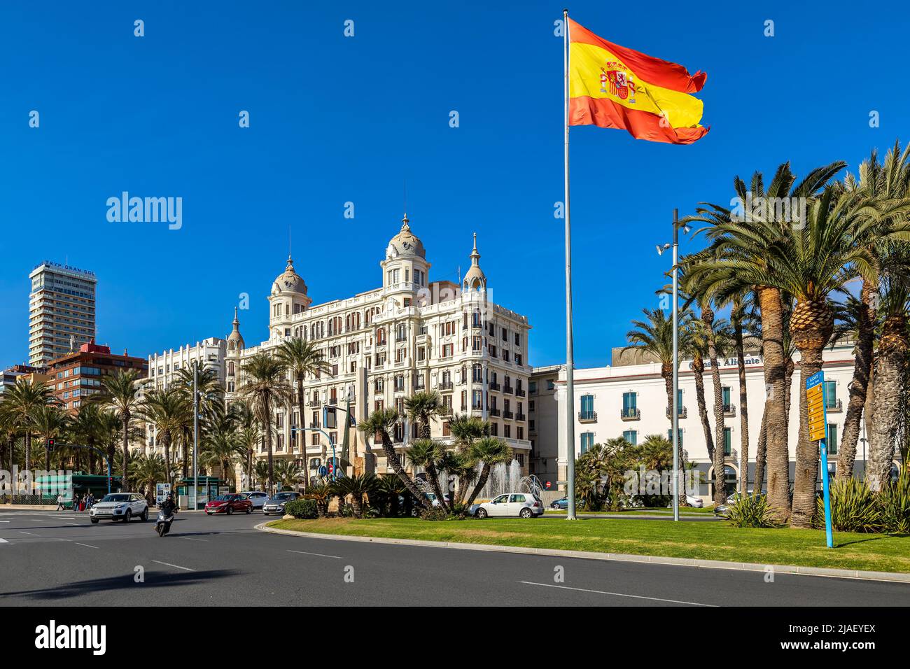 Spanish flag waving under blue sky in Placa del Mar - one of the main city squares of Alicante, Spain. Stock Photo