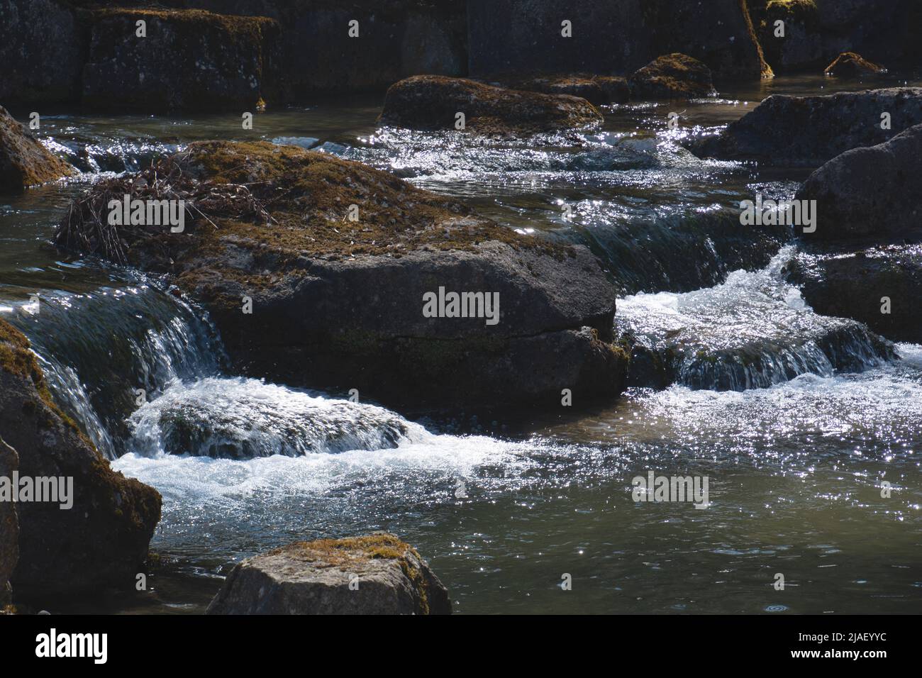 artificially created small stream with waterfall with big boulder Stock Photo