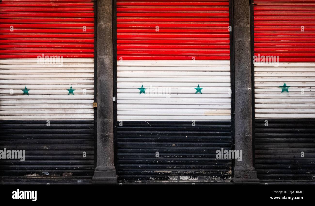 Damascus, Syria - May, 2022: Syrian flag on closed shop shutters in empty  market (Suq Al Hamidiyah) during Eid holidays in Damascus Stock Photo