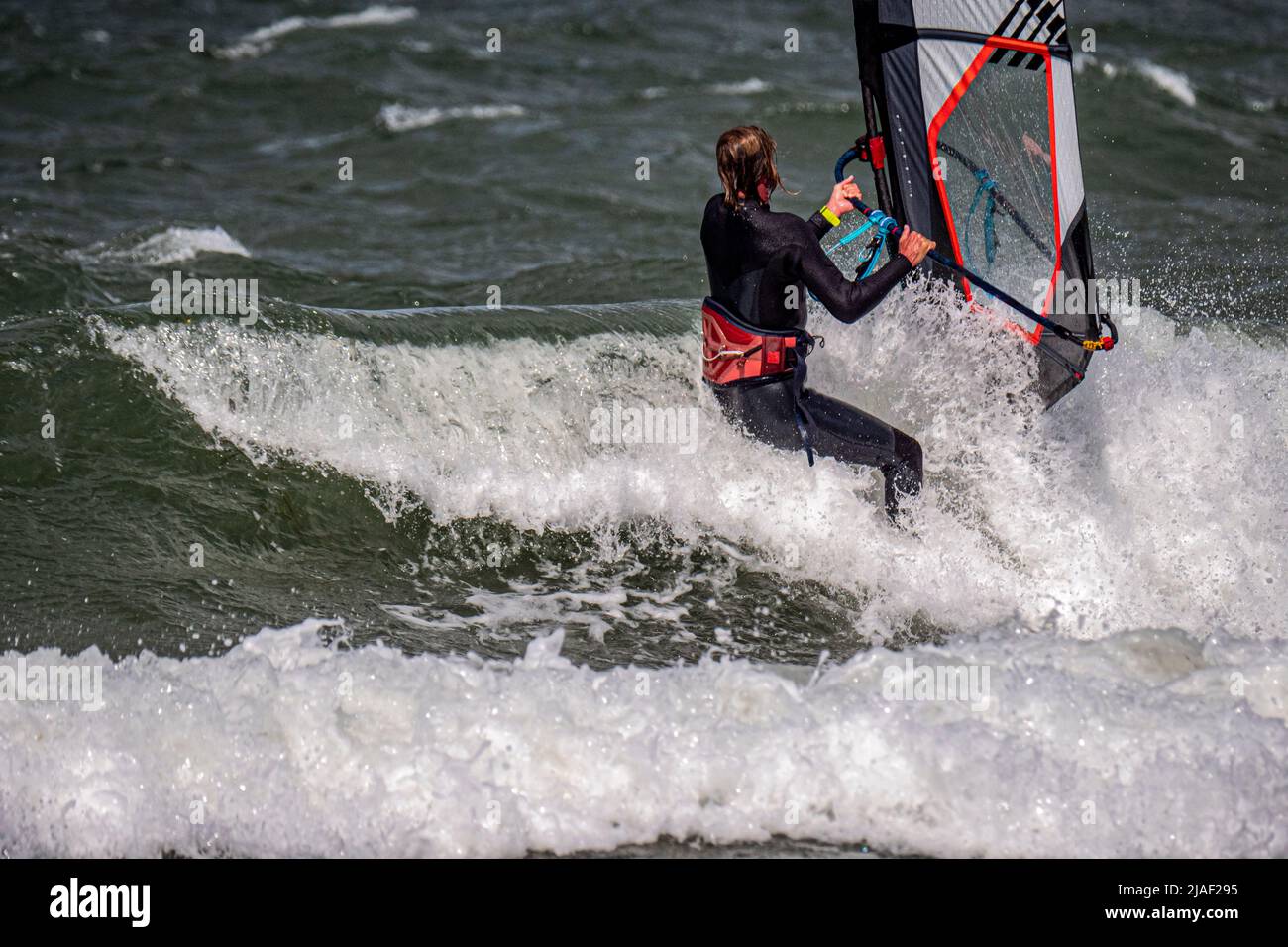 Windsurfer surfs through a wave. Close up. Stock Photo
