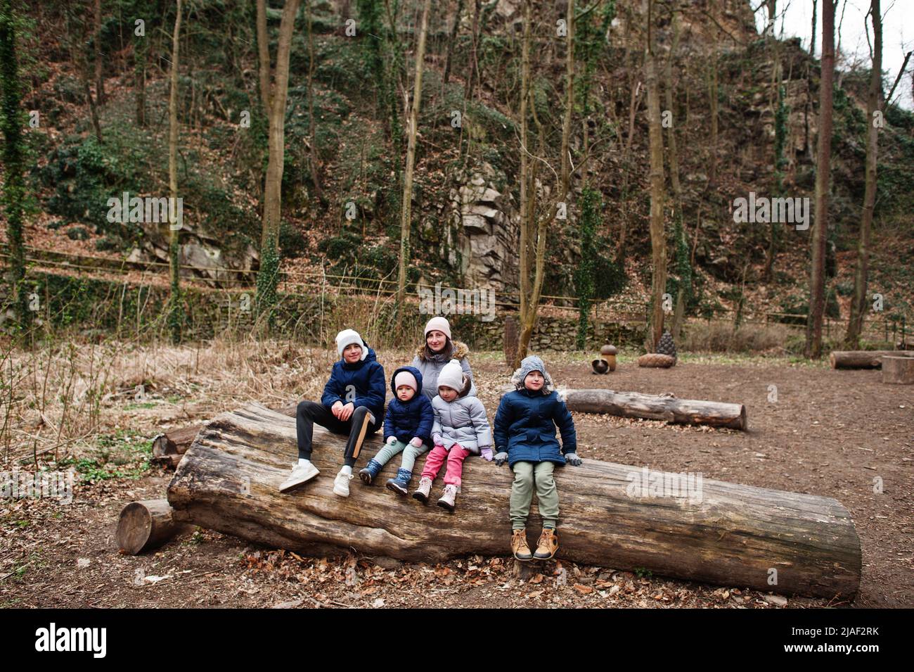 Mother with four children sitting on wood at Znojmo park in Czech Republic Stock Photo