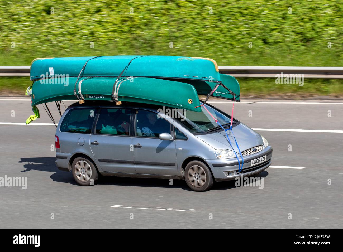 20006 silver Ford Galaxy1896cc Diesel SUV carrying three green Venture Canadian canoes on roof rack; driving on the M61 Motorway, Manchester, UK Stock Photo