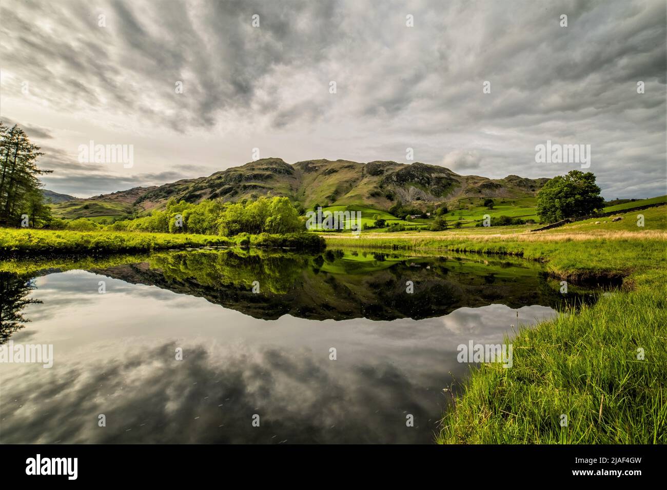 Little Langdale Valley, English Lake District, Cumbria, UK. 29th May 2022. UK Weather. Grey and cloudy day from the Little Langdale Valley in the English Lake District. View towards Lingmoor Fell, reflected in the infant River Brathay. Credit:greenburn/Alamy Live News. Stock Photo