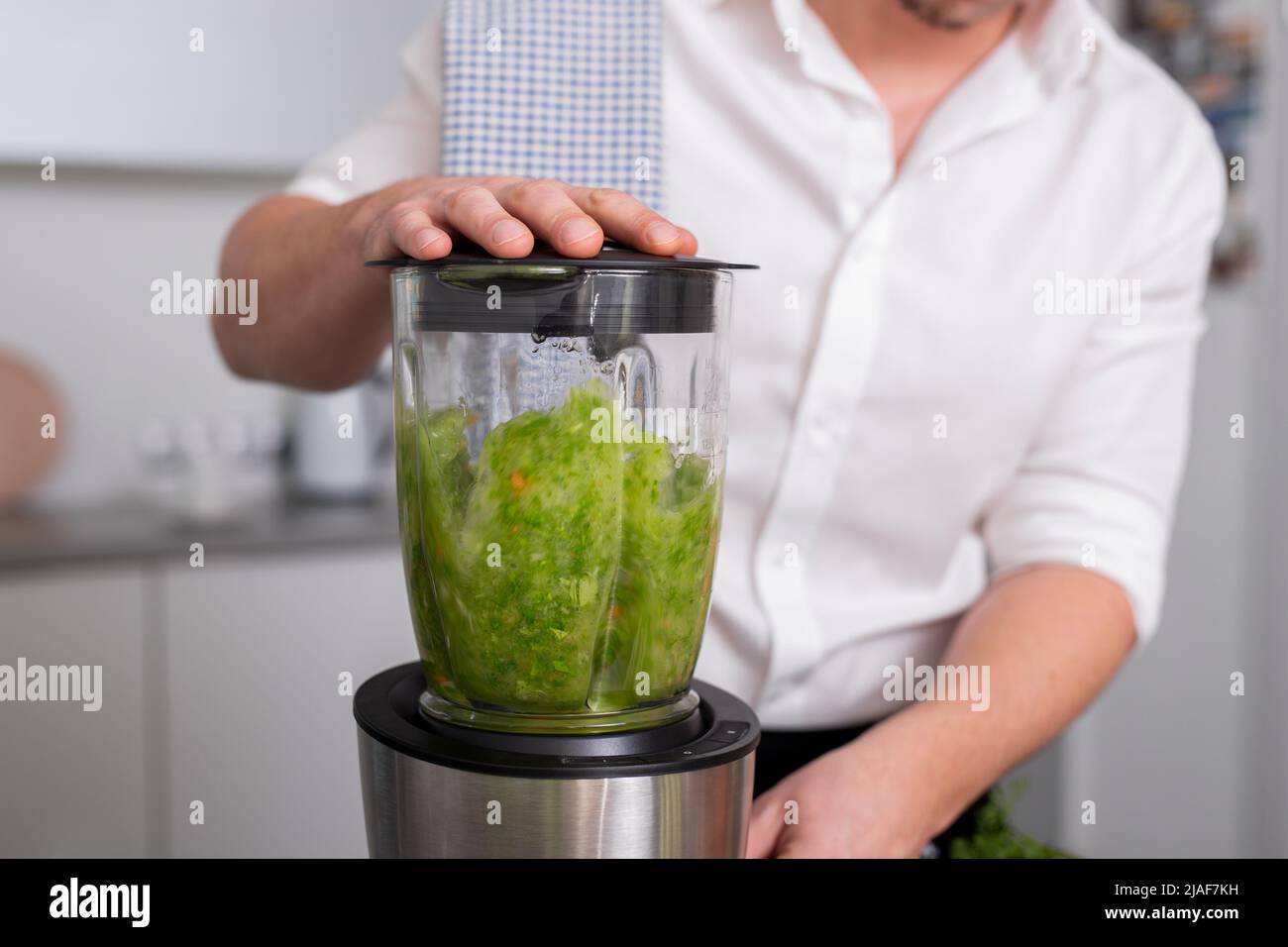 Unrecognizable man making green homemade smoothie in blender. Healthy