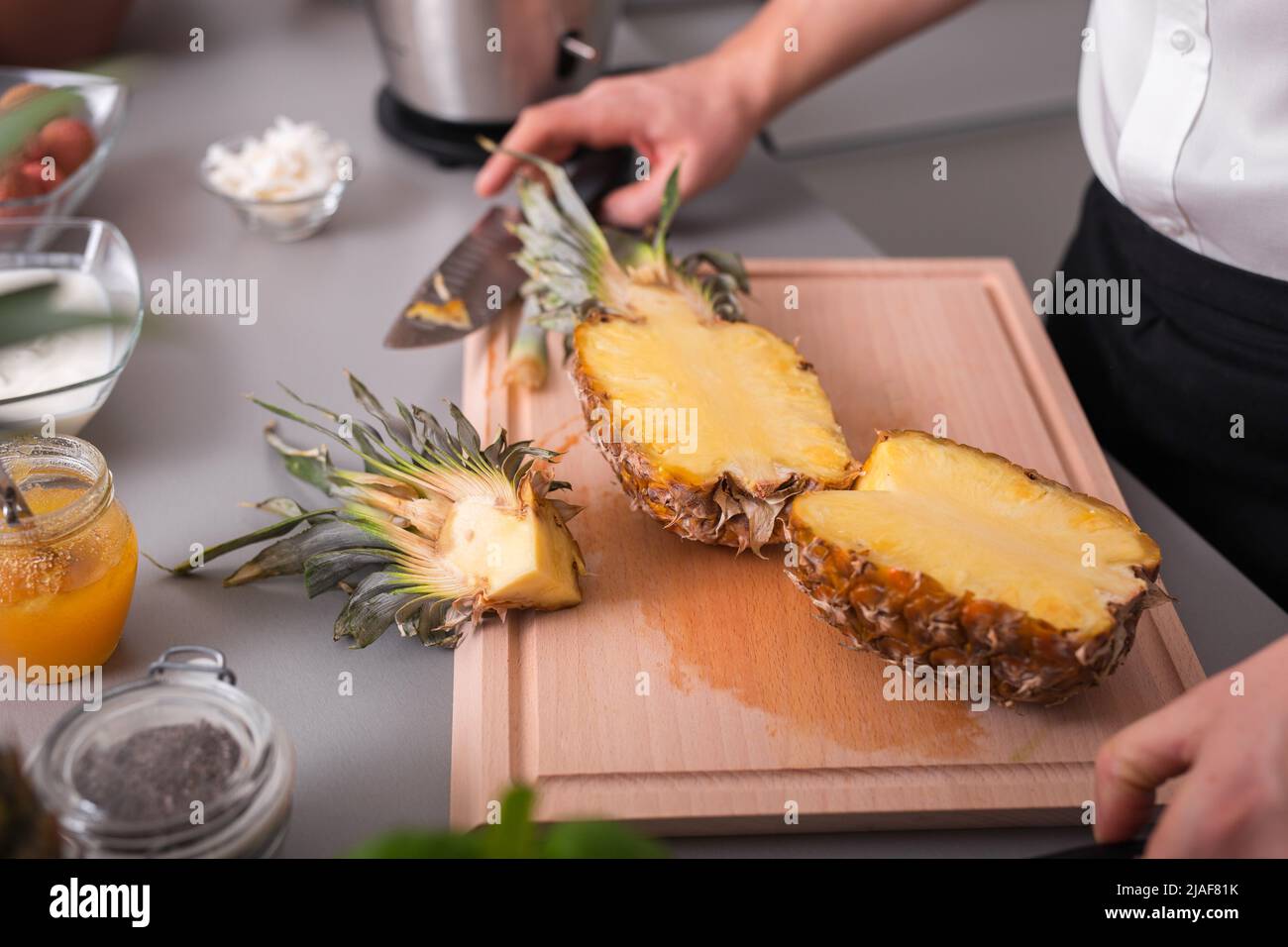 Unrecognizable man cutting a pineapple on chopping board. Stock Photo