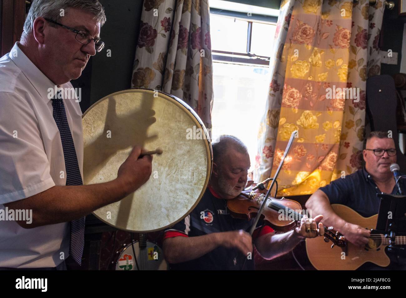 Traditional Irish music in a Donegal bar. A man plays percussion on a bodhran. Stock Photo