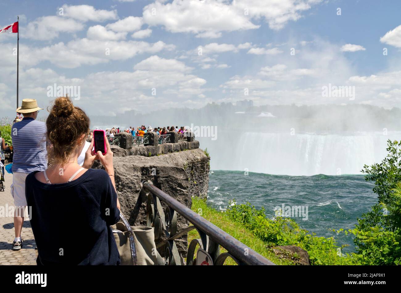 Woman taking a photo of Niagara Falls using her cell phone. in Niagara Falls, Ontario, Canada Stock Photo