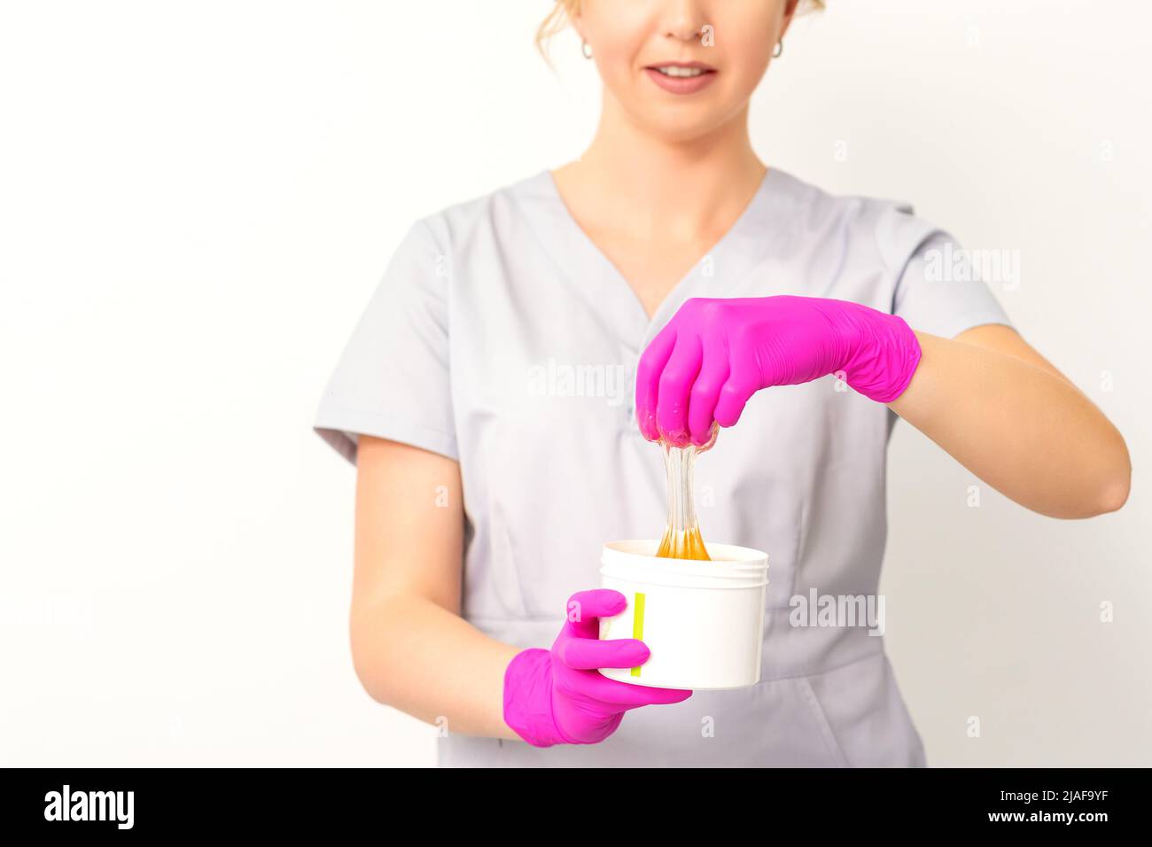 Portrait of a female caucasian beautician holding a jar of sugar paste
