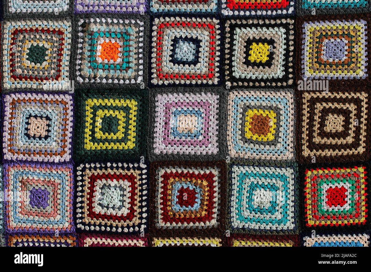 Detail of a crocheted patchwork multicolor wool blanket. Stock Photo