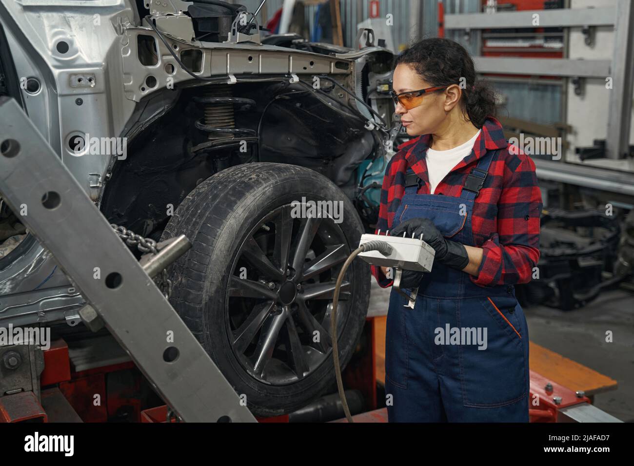 Female mechanic using diagnostic equipment in auto repair shop Stock