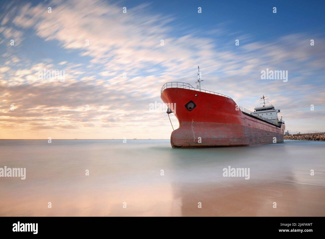 A Ship that run ashore during a sunset Stock Photo - Alamy