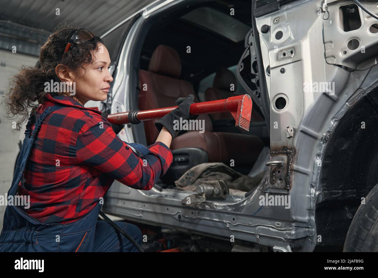 Woman auto mechanic repairing vehicle in car repair shop Stock Photo