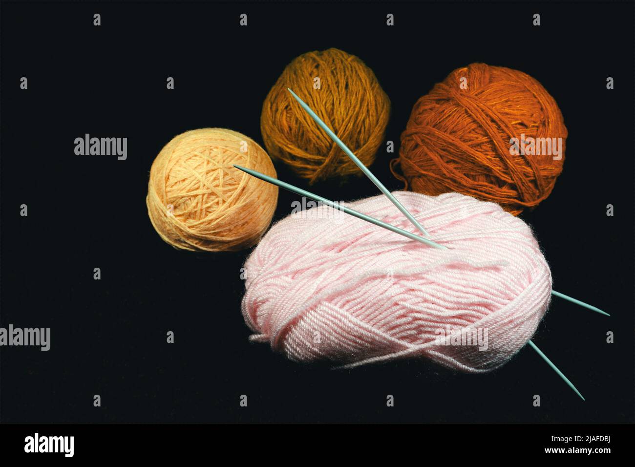 Colorful balls of yarn and knitting needles on a black background Stock ...