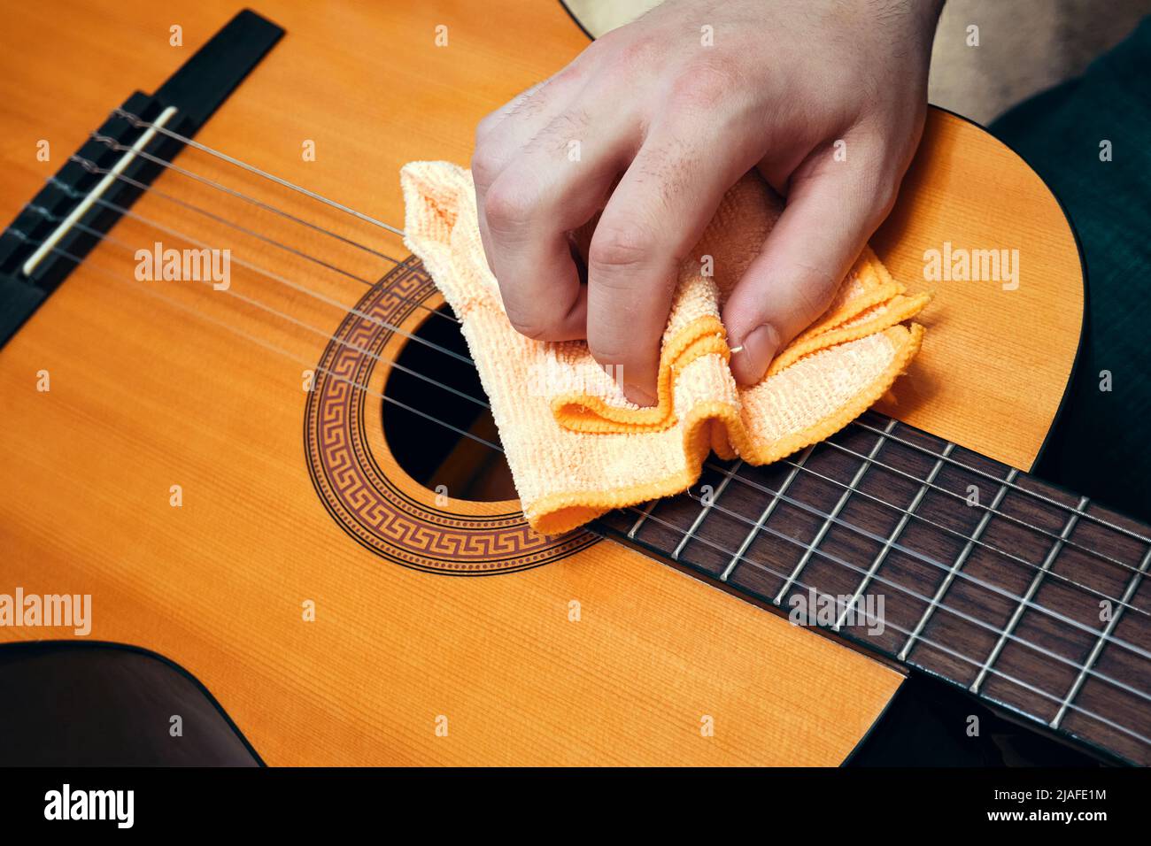 Musical instrument care. Guitar cleaning. Man cleaning a guitar Stock Photo