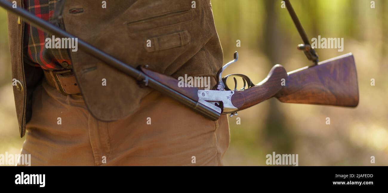 Close-up of hunter man carrying his rifle gun in forest. Stock Photo