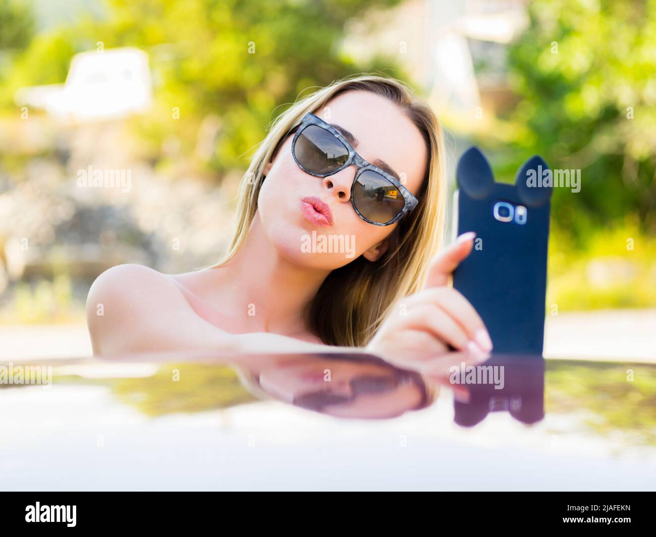 Adolescent teen selfie with fancy smartphone camera in hand wearing sunglasses Stock Photo