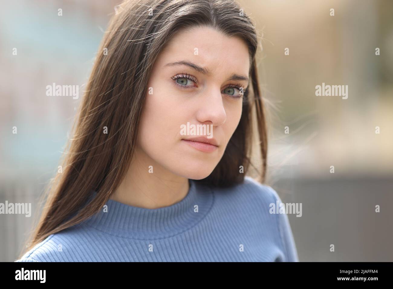 Portrait of an angry and suspicious woman looking at camera in the street Stock Photo