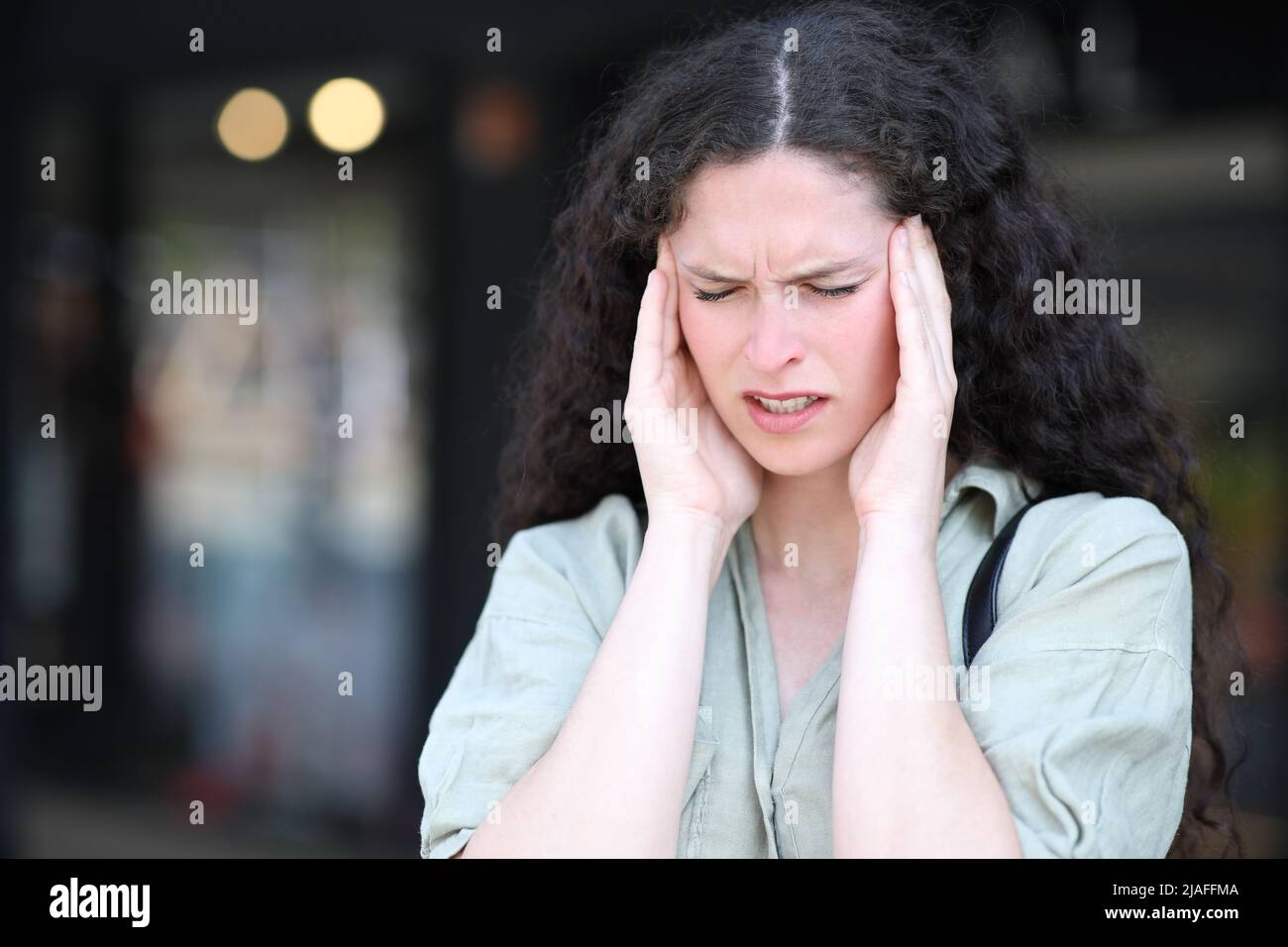 Stressed woman suffering migraine complaining in the street Stock Photo