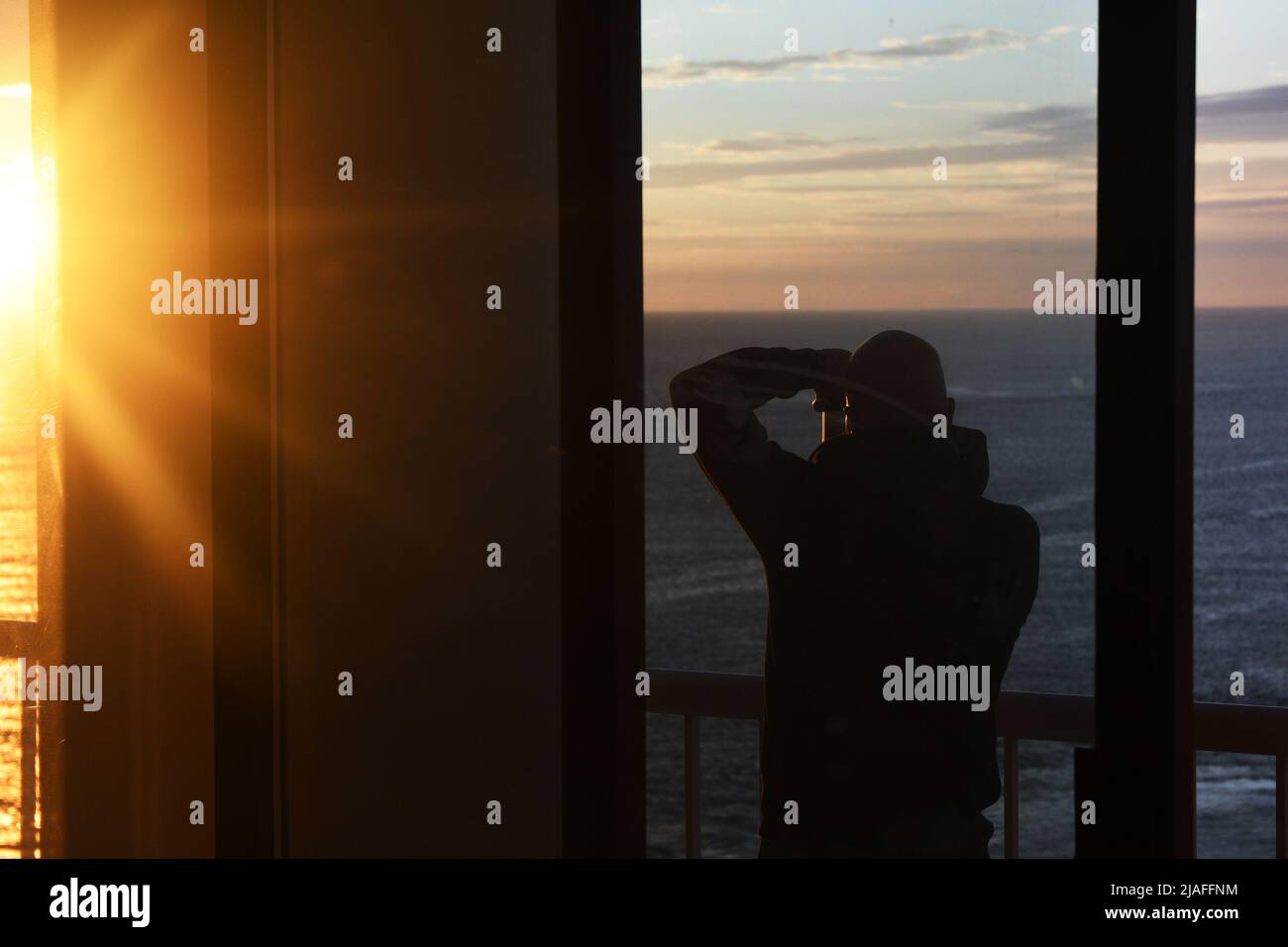 CLICK BAIT: A man wakes up at early dawn to photograph a beautiful sunrise off the Atlantic ocean on a high level balcony floor at the Flagship hotel Stock Photo