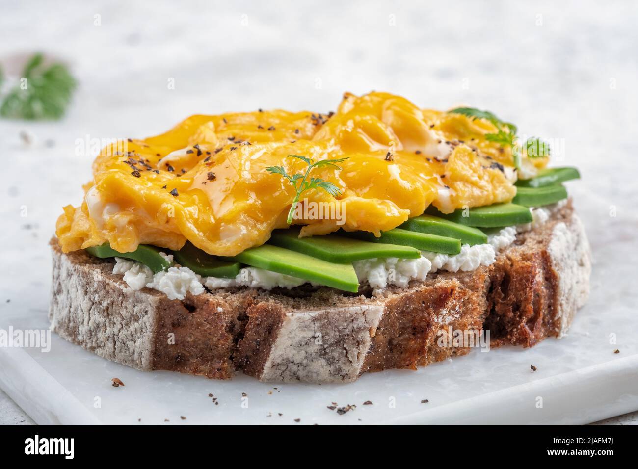 Scrambled eggs with avocado and cream cheese on toast Stock Photo