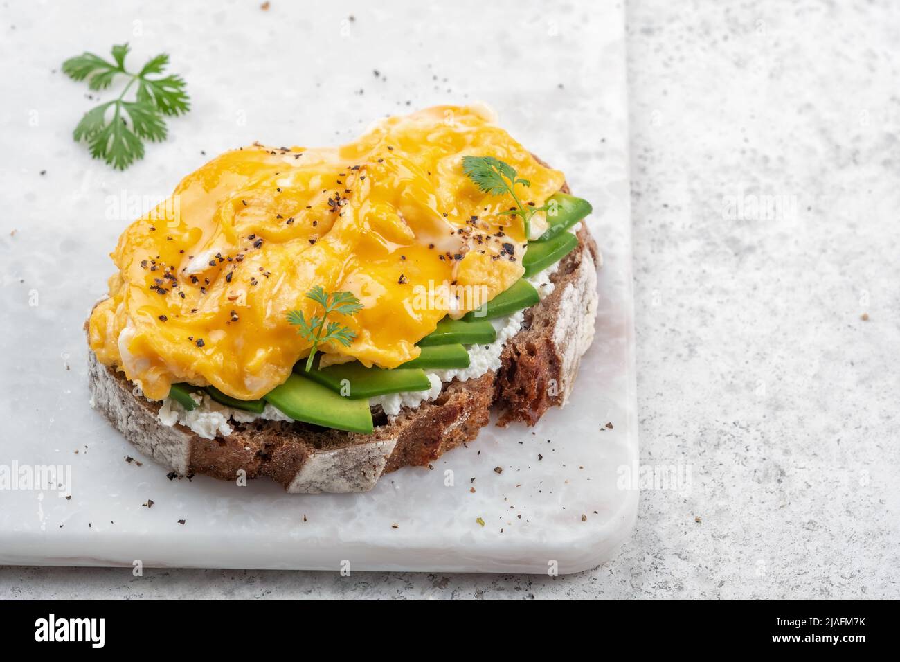Scrambled eggs with avocado and cream cheese on toast. Breakfast food Stock Photo
