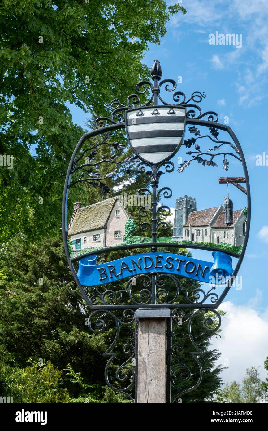 Brandeston village sign against foliage and lightly clouded blue sky Stock Photo