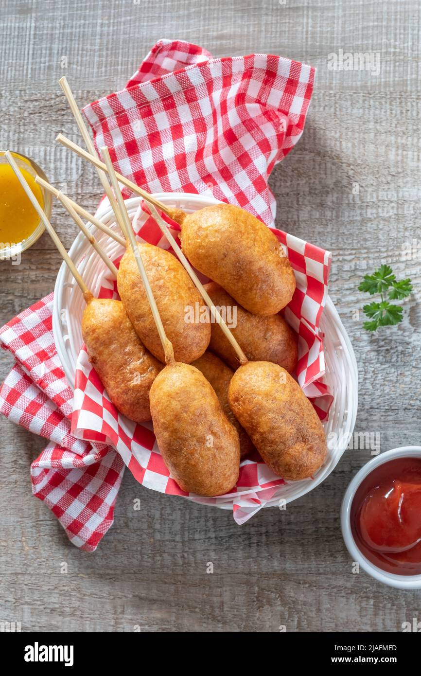 Traditional American street food corn dogs with mustard and ketchup on wooden table Stock Photo