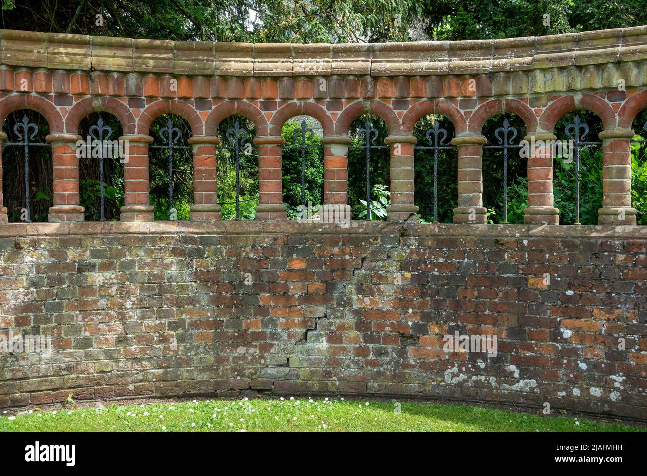 Ornamental curved brick wall with arches and columns and wrought iron Stock Photo