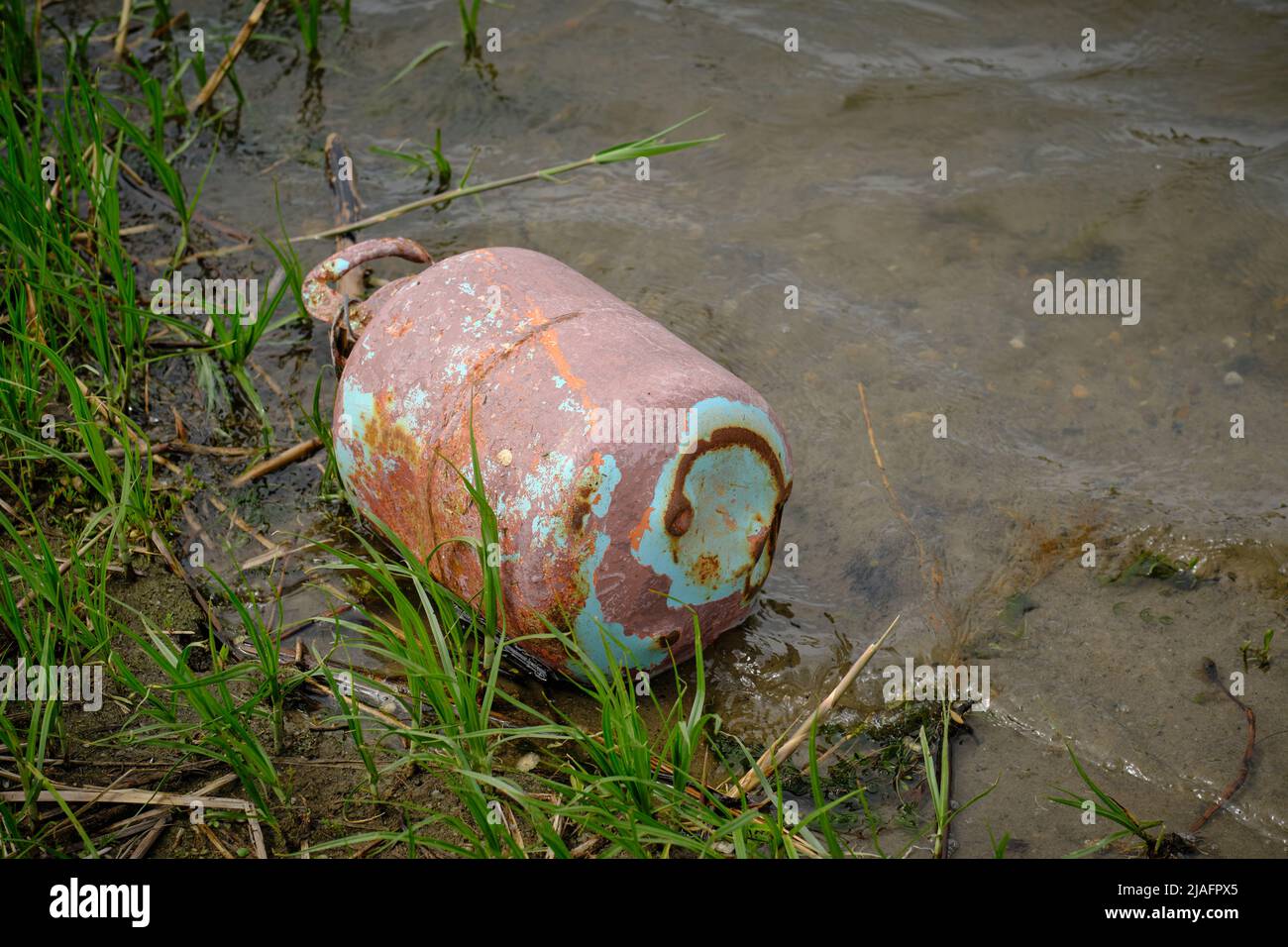 Old gas cylinder riverbank, pollution of ecology and nature Stock Photo