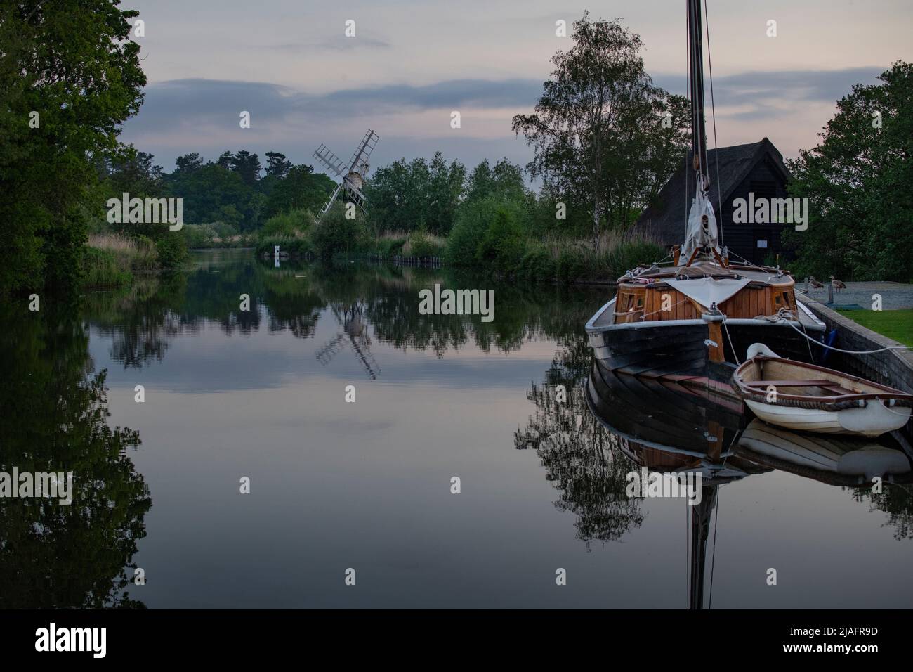 Norfolk Broads Norfolk Dawn England May 2022 The River Ant and Boardmans Drainage Mill at How Hill on the Norfolk Broards. Hathor Wherry on right. The Stock Photo