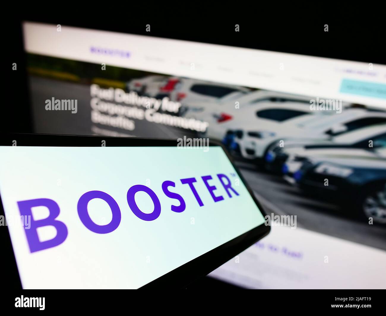 Mobile phone with logo of American energy delivery company Booster Fuels Inc. on screen in front of website. Focus on center of phone display. Stock Photo
